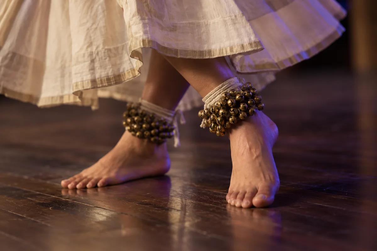 Kathak dancer's feet with ghungroo bells on a wooden floor
